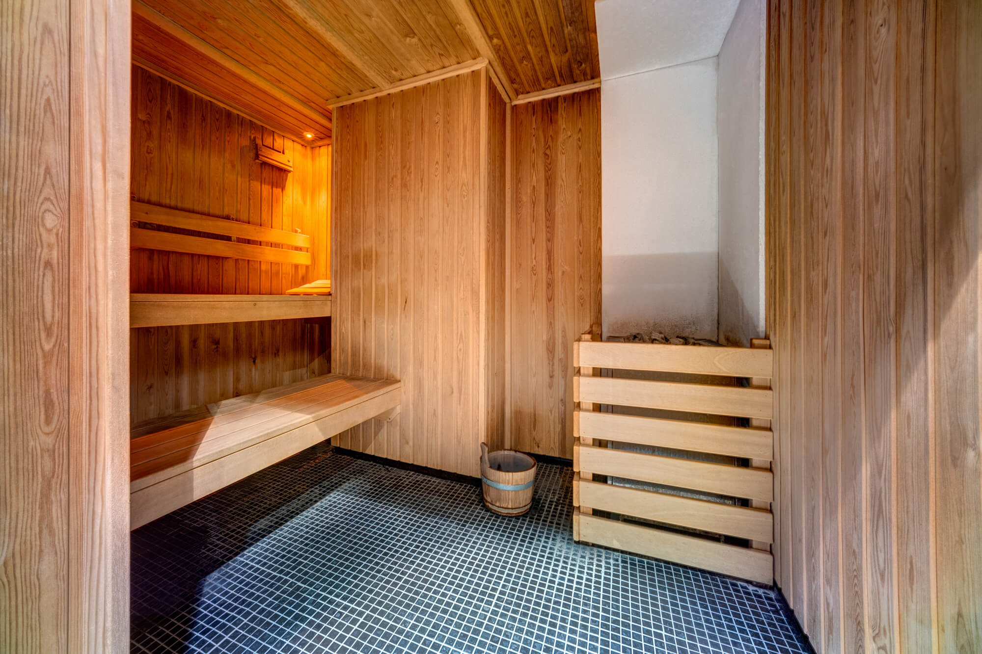 Sauna with blue and white floor tiles and wooden wall panels and seating