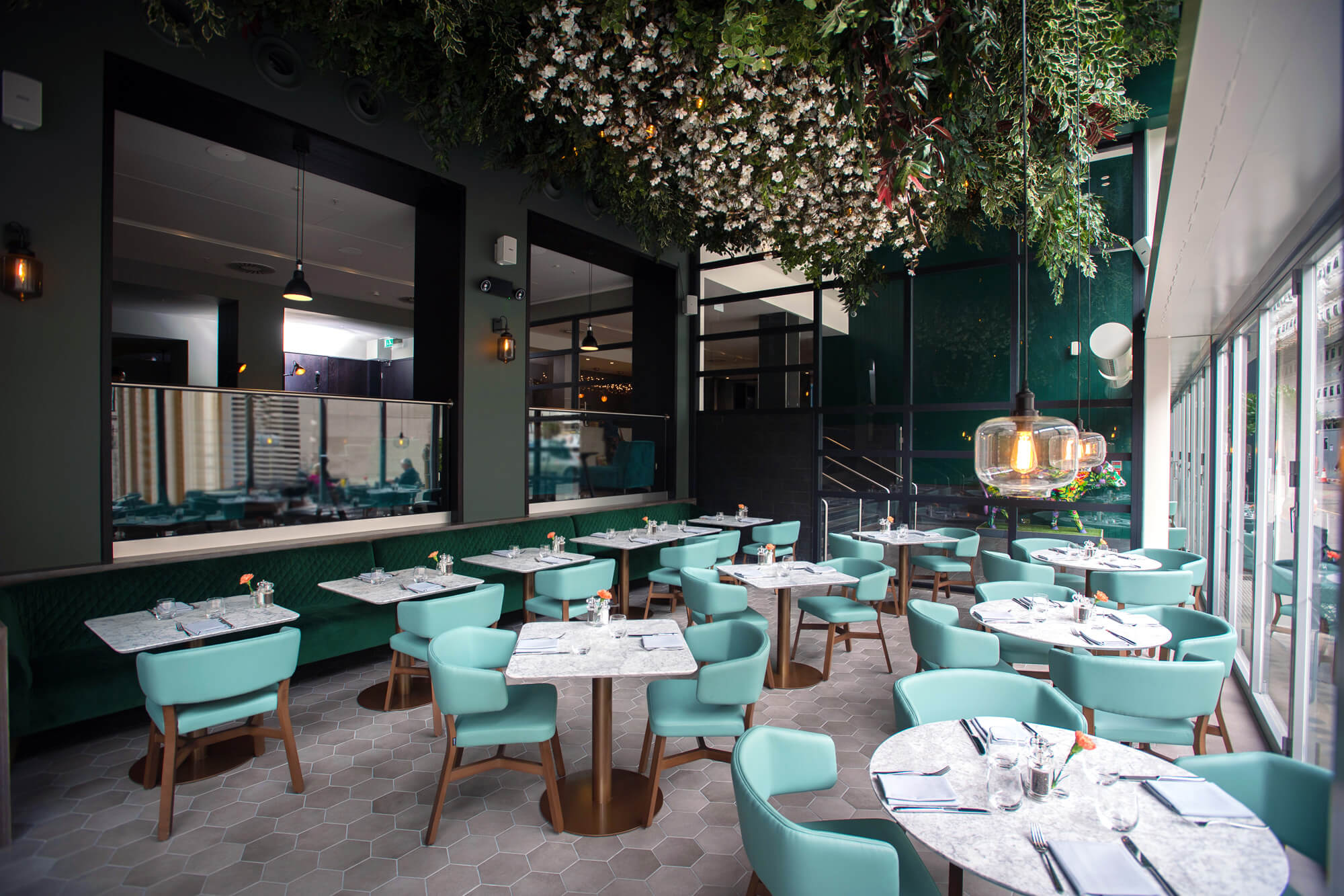 Tables and chairs set up under the floral canopy at The Lampery