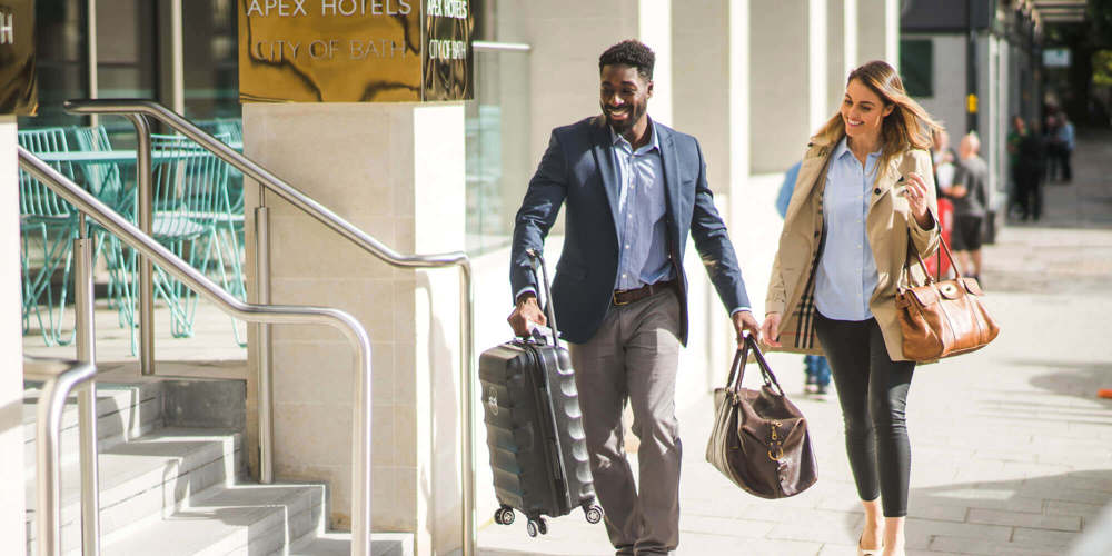 Female guest being helped with luggage into hotel by employee