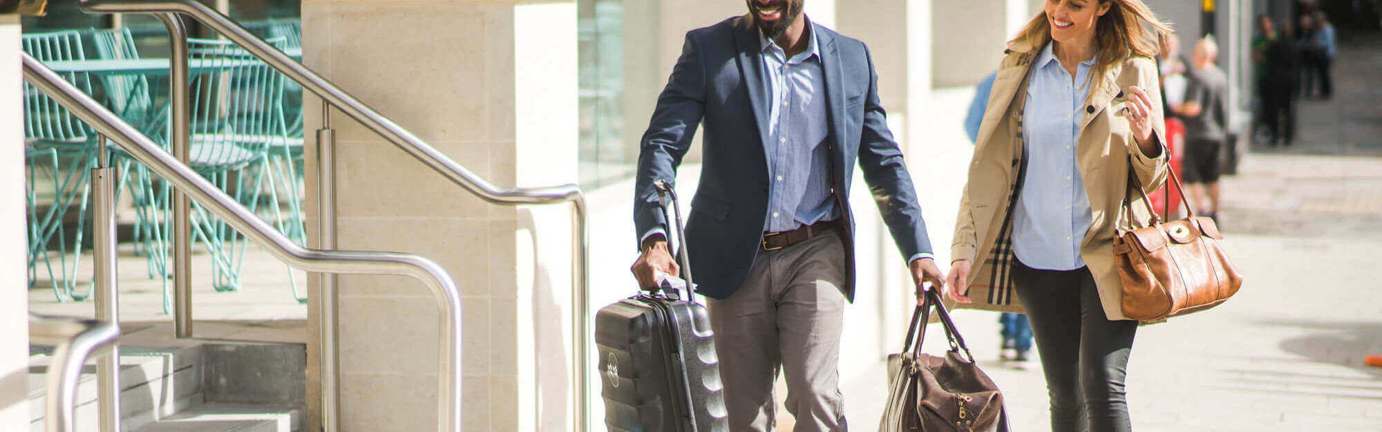 Female guest being helped with luggage into hotel by employee