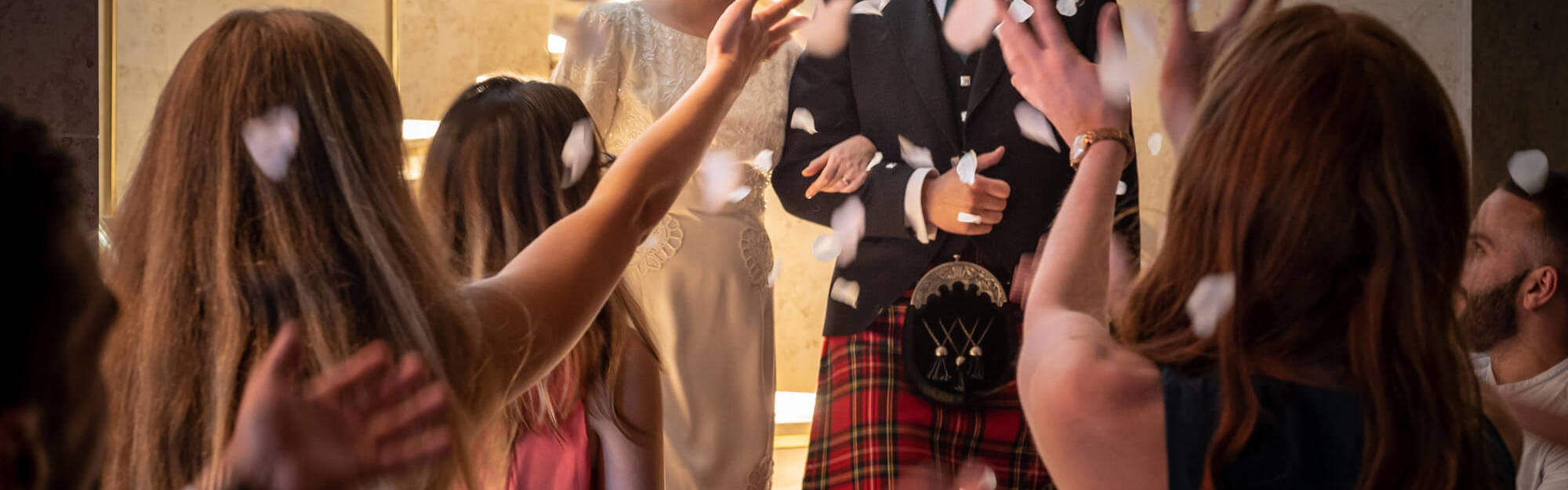 Newly married couple with crowd throwing confetti