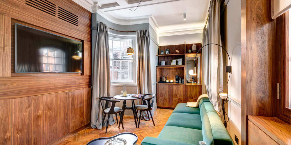 Grand Suite living area with velvet sofa and traditional wooden features