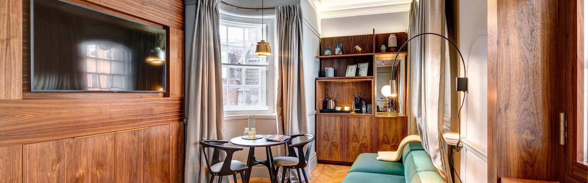 Grand Suite living area with velvet sofa and traditional wooden features