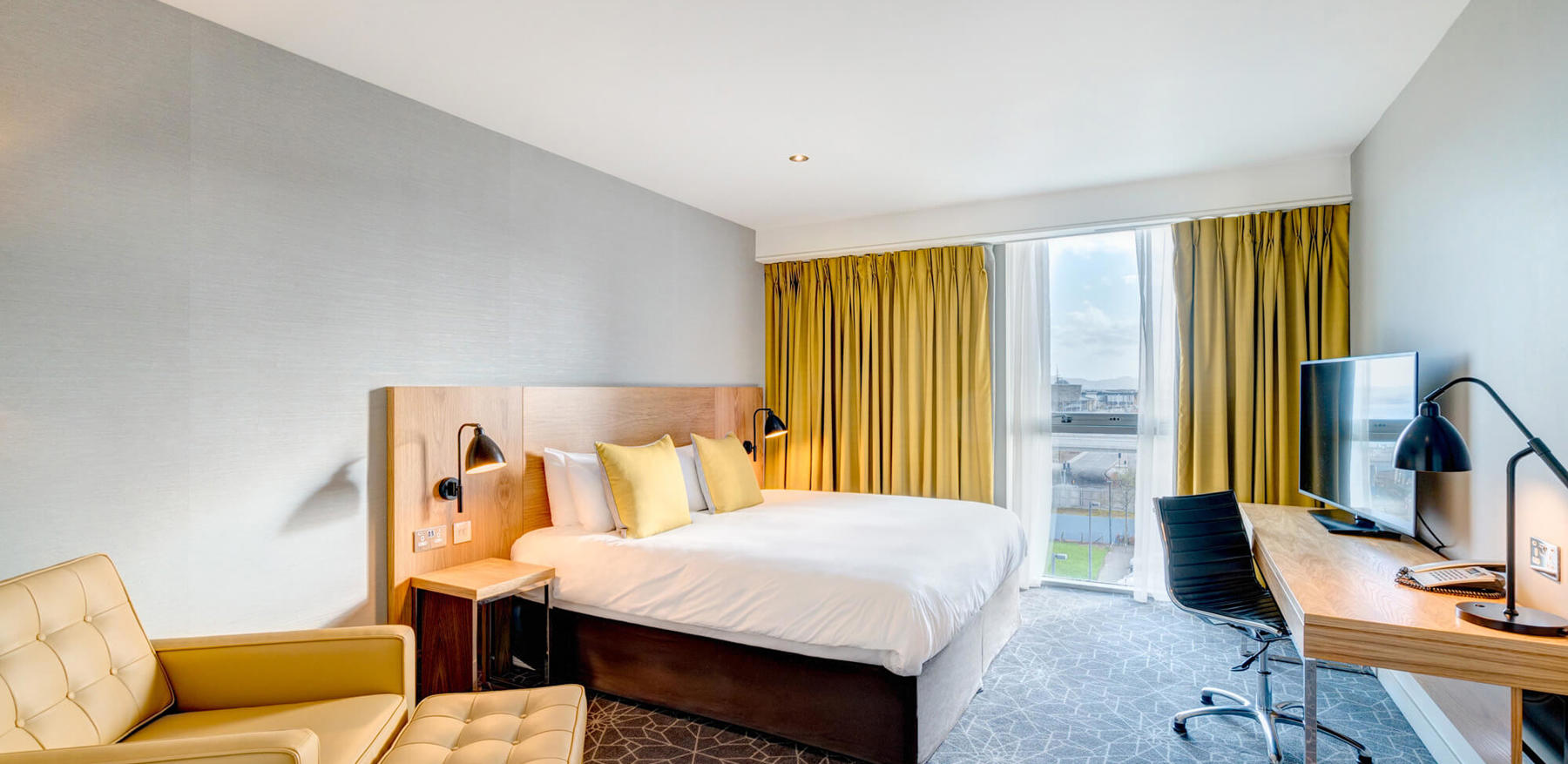 King-size bed with armchair and desk with TV