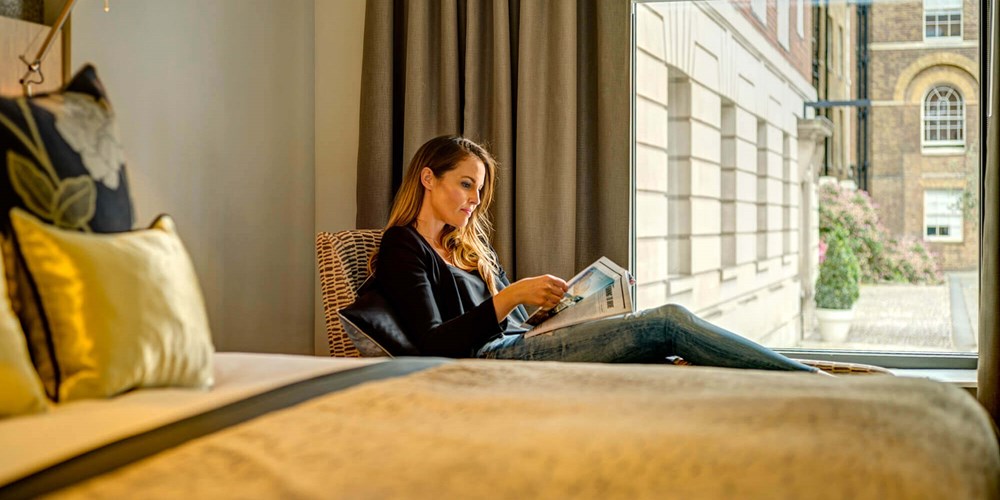 Female guest reading magazine in bedroom at Apex Temple Court Hotel