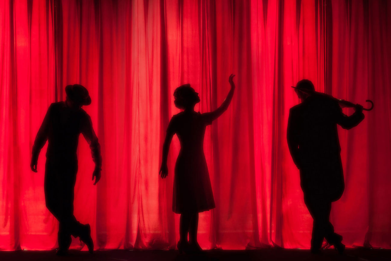 Theatre performer shadows in front of red curtain