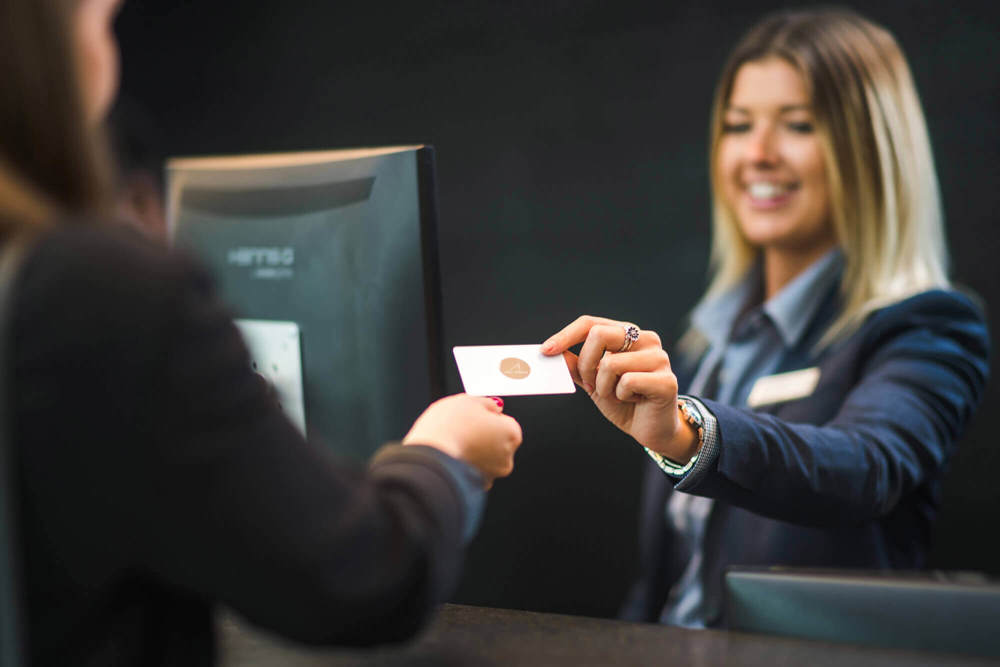 Receptionist handing over key card to guest at check in Receptionist handing over key card to guest at check in