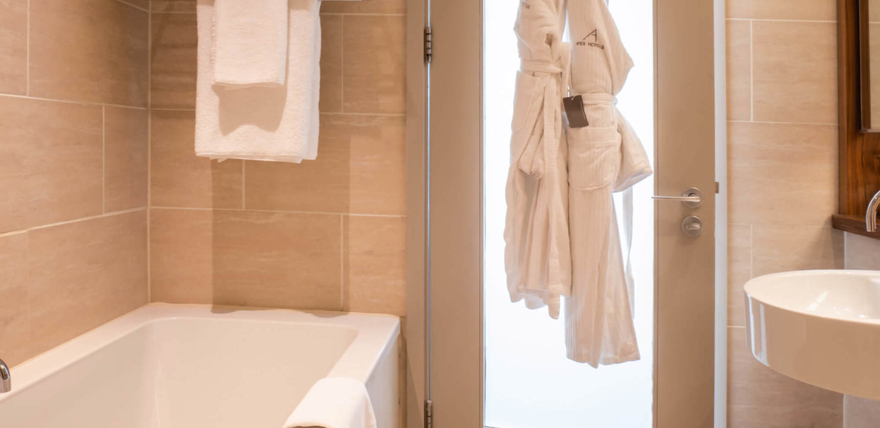 Family Room bathroom with bath and robes hanging on door at Apex Waterloo Place Hotel