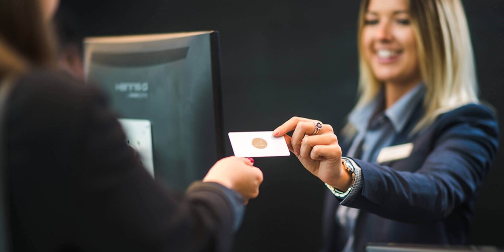 Receptionist handing over key card to guest at check in